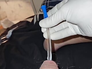 Wearing surgical gloves and inserting a catheter into the penis