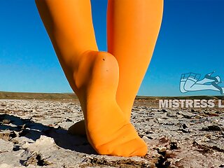 Barefoot walking by dried up lake in yellow pantyhose